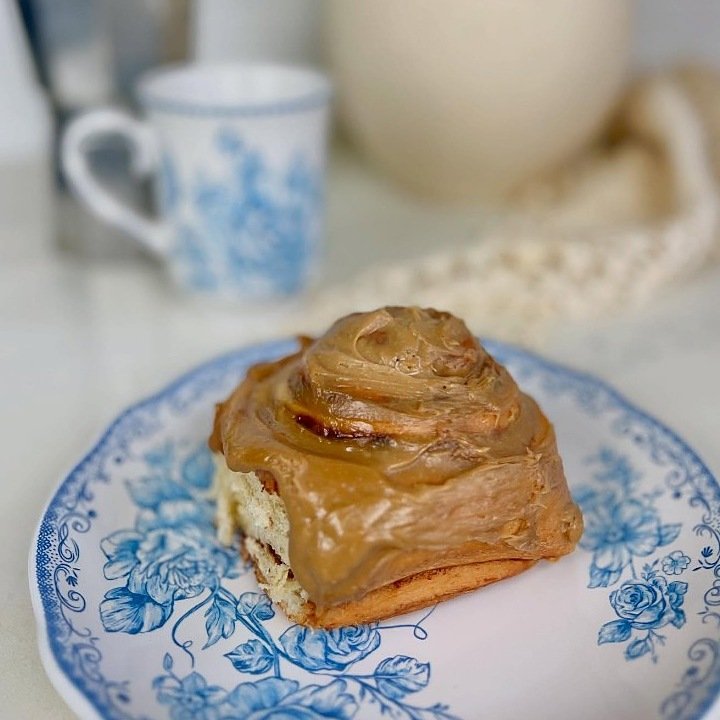 Fresh cinnamon roll with cream frosting on a blue floral plate